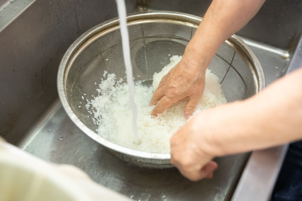蒸した米を洗う