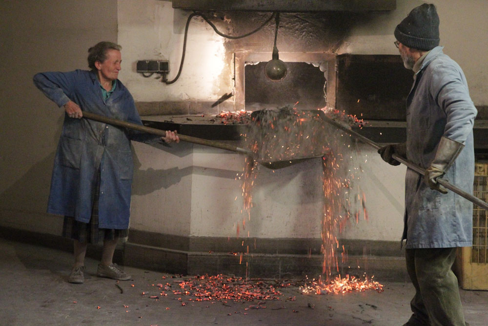 炭を掃き出す作業。鎌形をした長い棒や大スコップなど、代々使い続ける道具は考え抜かれた無駄のない美。