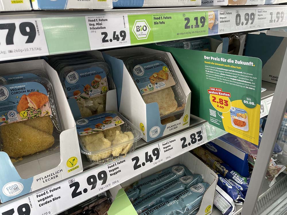 （写真）ヴィーガンのカツレツ（シュニッツェル）は通常価格2.69ユーロに、気候0.04ユーロ、水0.01ユーロ、土地0.07ユーロ、健康0.02ユーロが加算されて2.83ユーロに。値上がり率はわずか５%ほどだ。