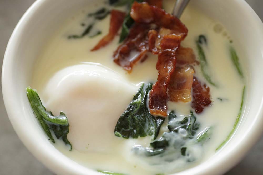 冷凍ホウレン草を加えてからレンジで加熱し、カリカリに焼いたベーコンをのせて洋風に。