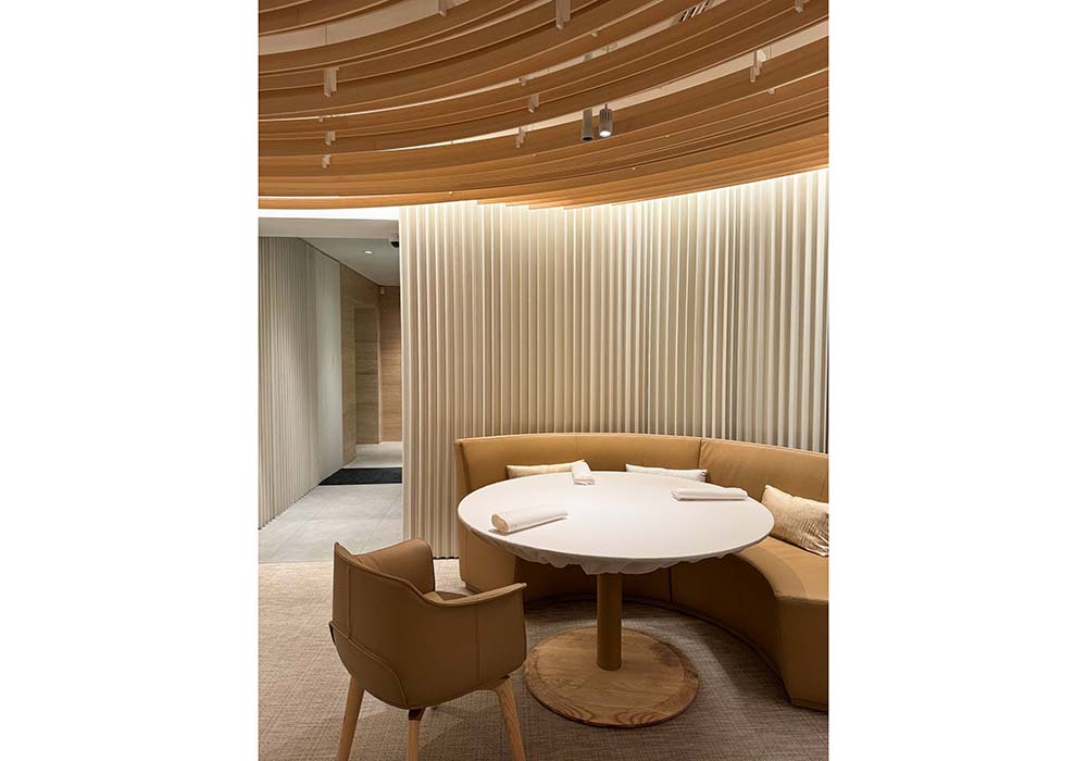 （写真）隈研吾氏による内装は、白と木の色が基調になっていて、柔らかく無垢な空気感。日本的な「自然」も感じられる。入口の横には個室があり、バーカウンターを抜けて、メインホールに進む。メインダイニングの壁は反響音を遮断するためTexaa社から特別な素材を配置、床はオニキスの天然石だ。