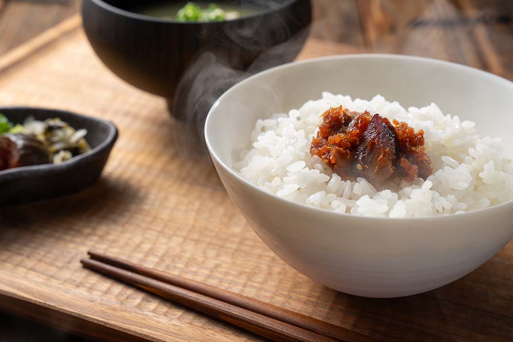 看板商品の「漁師のラー油かつお」（￥700・税込）を乗せたご飯。ラー油は、ニンニクの利いた奥行きのある味わい。企業組合のある高知・久礼は、400年以上前から“カツオの一本釣り”が盛んな漁師町。港で水揚げされたばかりの新鮮な魚が並ぶ久礼大正町市場では、とれたての生カツオが食べられる。