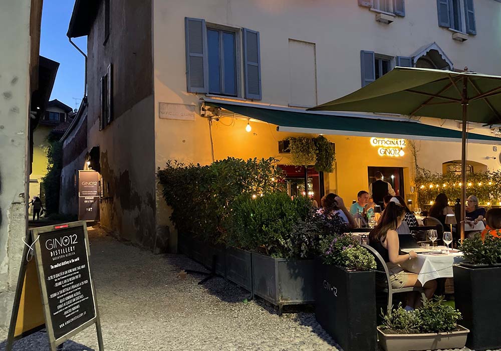 （写真）ナヴィリオ地区は、ミラネーゼをはじめツーリストたちにも人気のナイトスポット。遊覧船も運行する水路の両サイドには飲食店が立ち並ぶ。その中の１軒、ジン専門バール「ジーノ12」のテラス席の角を曲がると「ジーノ12 ディスティラリー」のドアが見える。新しい移転先は、この突き当たり、数メートル離れたところ。