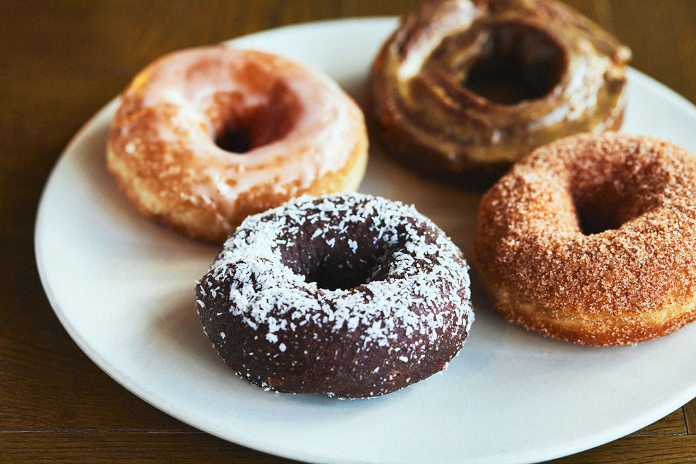 基本のヴィーガン菓子パン生地を揚げて作るヴィーガンドーナッツ。程よいヒキが適度なボリュームを感じさせる。（左奥から時計回り）レモン、コーヒーオールドファッション、シナモン、ココナッツ。