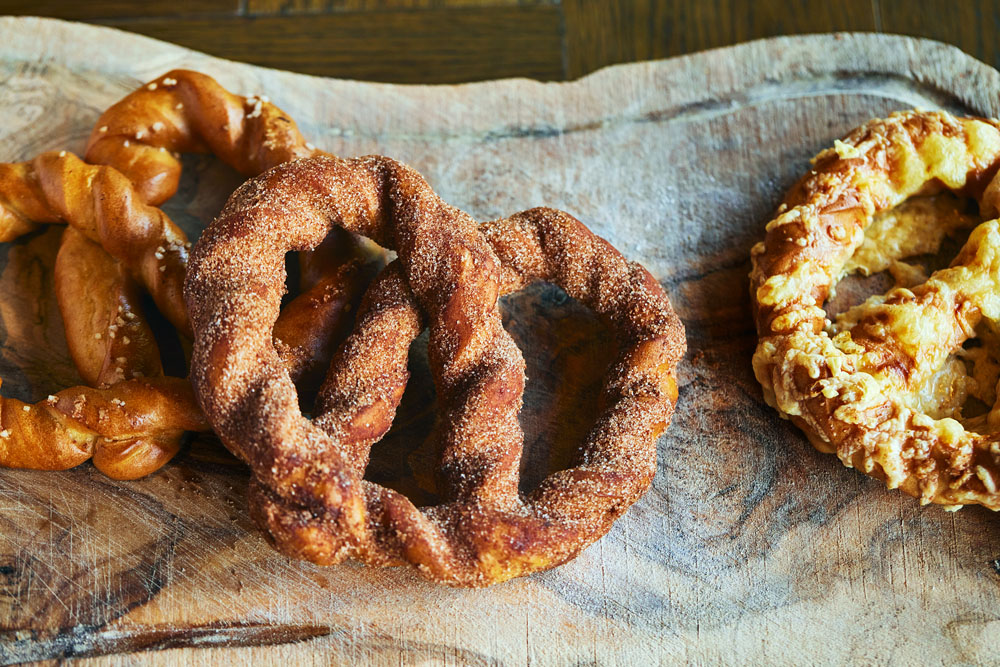 日曜限定から、平日にも定番として提供するようになったヴィーガンプレッツェル。ベース生地はヴィーガンで仕込み、トッピングだけでノンヴィーガンにも対応する。（左から）プレーン、シナモン、チーズ。