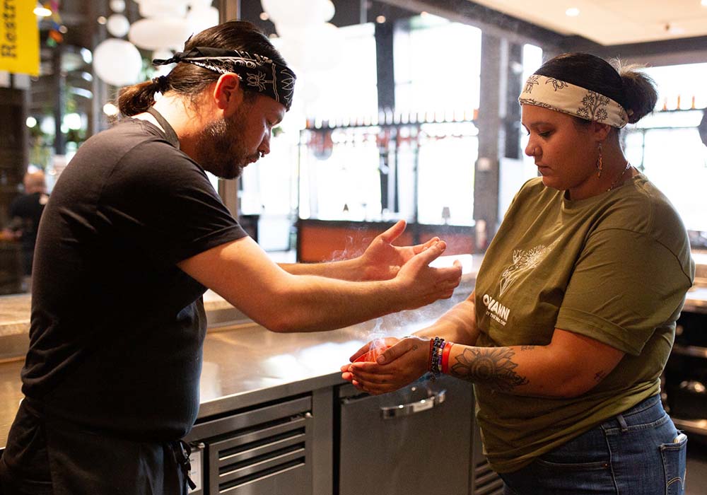 （写真）調理前のお清めの儀式、スマッジング。セージ、杉やスイートグラスと呼ばれる草を燃やした煙を自らの体にかける。浅草寺などの香炉を使ったお清めの作法に通じるものがある。photograph by Sean Chee