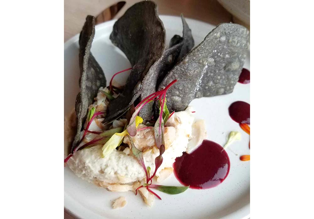 (写真)オワムニのメニューより、「テパリービーン（白インゲン）とスモークした鱒のディップ、ウォジャペ（ベリーソース）とトーストしたコーンチップス添え」（14ドル）。かつて中西部のタンパク源といえば他に、ウォールアイ（白身の淡水魚）、七面鳥、ヘラジカ、バイソン、コオロギなどで、季節に応じてメニューに登場する。photograph by Gail Irish