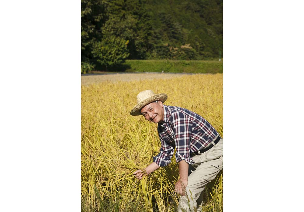 今井隆社長。自社の目の前の田んぼでは無肥料、無農薬で栽培している。
