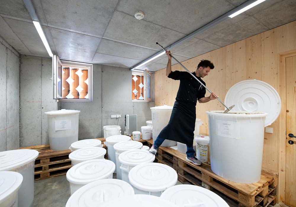 （写真）イタリア各地から集めた余剰食品を発酵させ、シェフ自らガルムをかき混ぜて、発酵具合を確かめる。麹を使うことで、本来のガルムの欠点とも言える腐敗に近い臭いは生まれず、発酵食品が苦手な人でも楽しめる香りのよいガルムが生まれる。