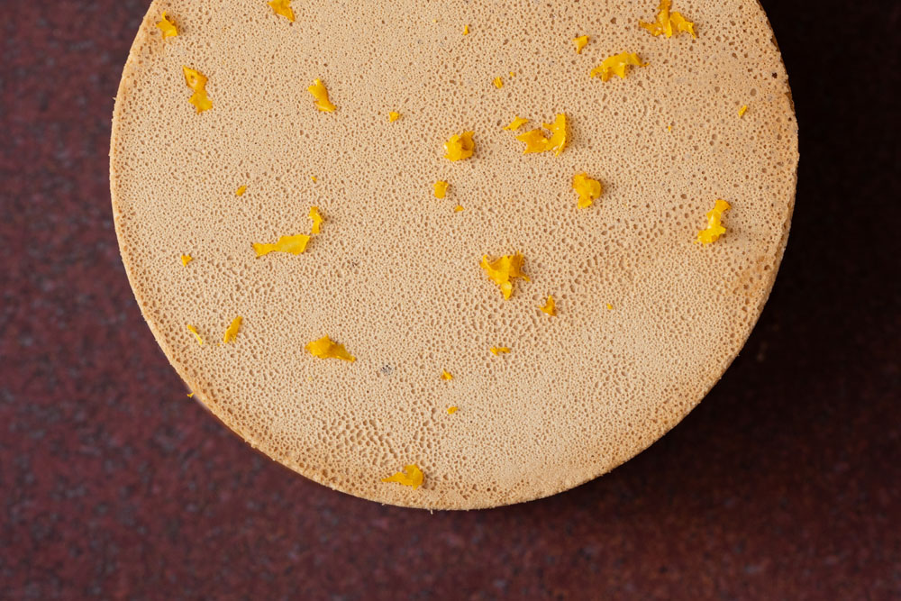 「伊江島産黒糖のメレンゲ　柚子ソース」。伊江島で目にした赤土に思いを馳せ、赤土でつくられた皿にのせ、すりおろしたユズの皮を散らす