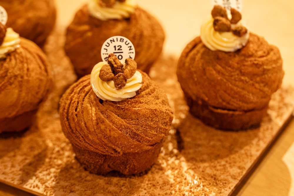 「ジュウニブンベーカリー」で販売される、「伊江島黒糖のクロフィン」。トッピングには、練乳とバターを加えたミルククリームを絞り、黒糖がけしたクルミを添える。