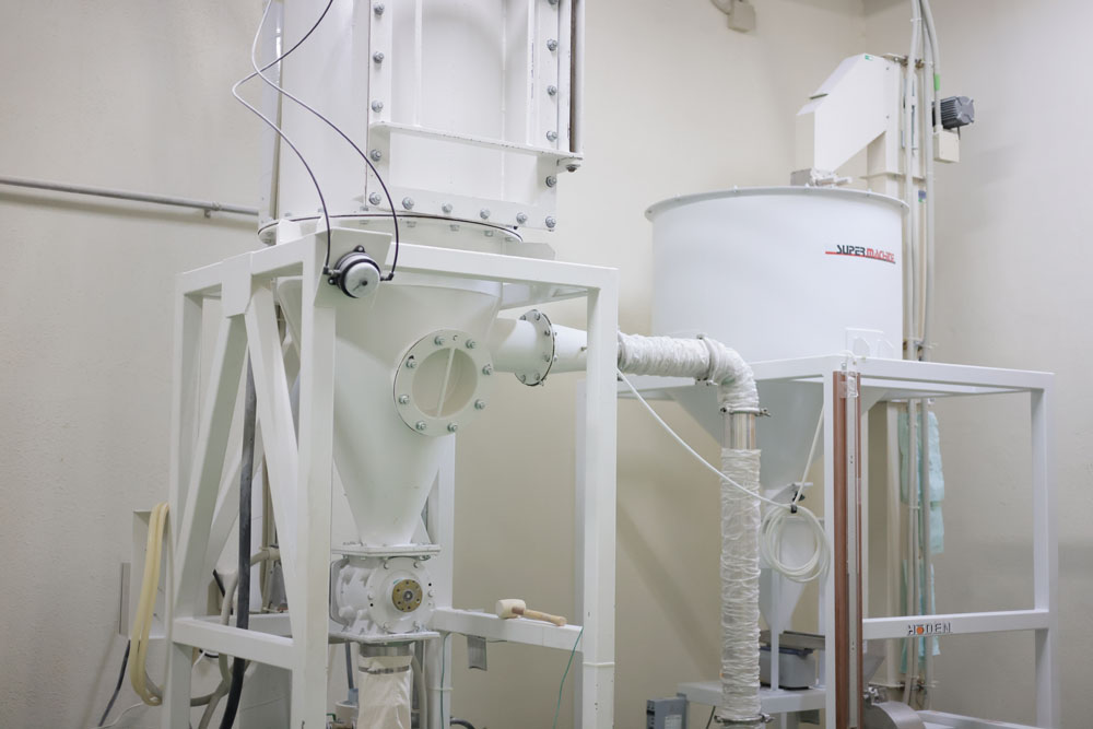 精麦機でていねいに削ってフスマを取り除いた後、気流粉砕機（写真左）で直接的な圧力をかけず、ダメージをできるかぎり与えずに粉砕。これによって、栄養価が高い小麦粉に仕上がる。その後、ふるい機（写真右）を通してから袋に詰める。