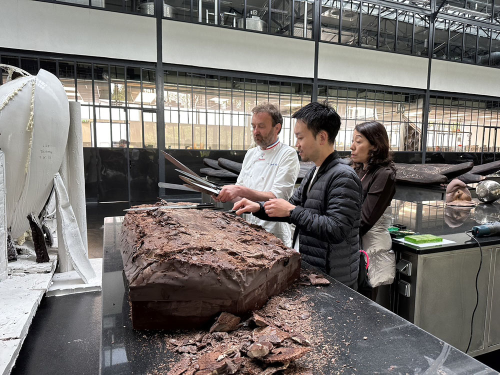 パリ郊外にあるパトリック・ロジェのアトリエで。ロジェはチョコレートの彫刻でも知られる芸術家肌のMOFショコラティエ。五藤さんも彫刻刀を使ってチョコレートの塊を削ってみた。