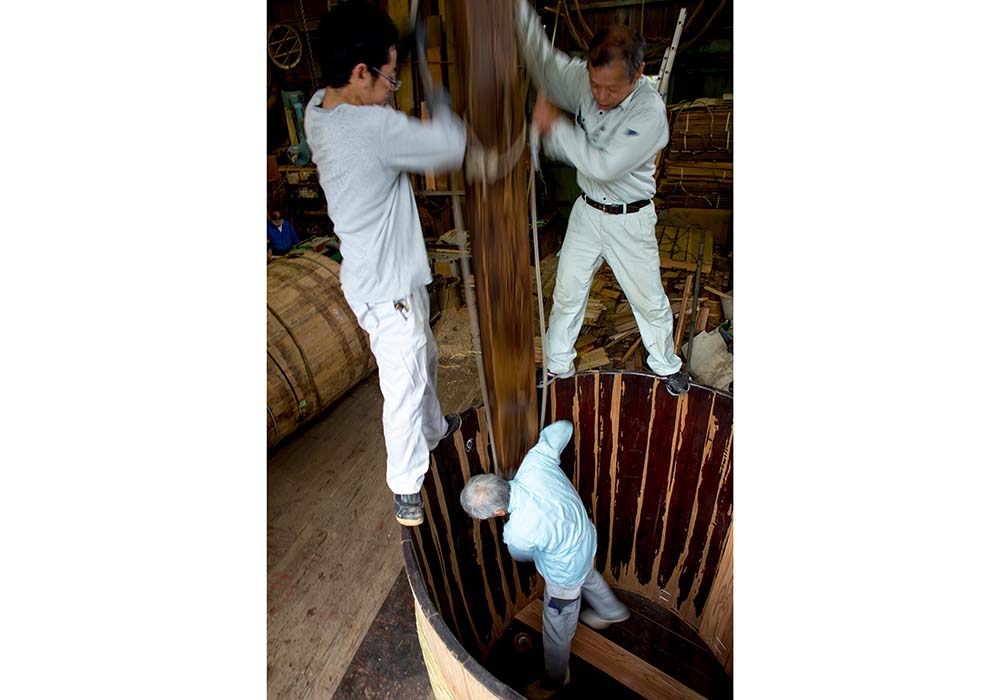 「や～そ～れも～やさ」。底板を「胴突き」で入れる際の掛け声。体操の平均台も真っ青になる高さと不安定な足場での作業だ。