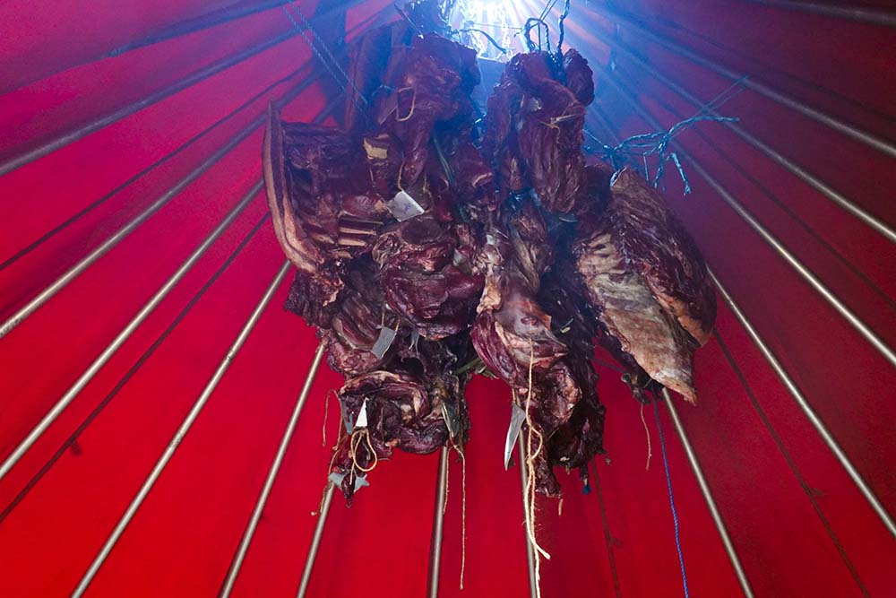 （写真）ラヴヴォの中で燻製中。一度火をつけたら、火の加減をみる担当者以外はできる限り出入りはしない。外気が入ると出来上がりにさらに時間がかかるためだ。自分の肉がどれかわかるように、肉には名札がつけてある。