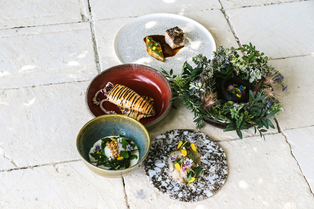 野菜、トマト、ハーブに加え、ティミリアなどの古代穀物、オイル、柑橘など、地元の食材が主役。燻製、直火、オーブンを駆使したユニークな料理が並ぶ。©Victoria Holguin