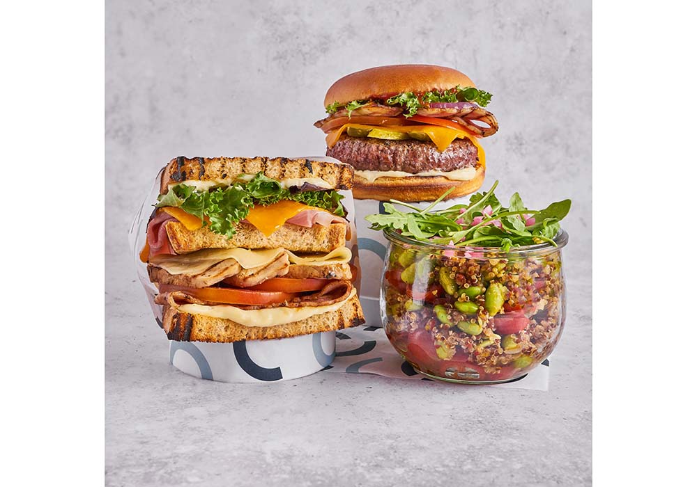 （写真）左からクラブサンド17.50ユーロ、クラッシックハンバーガー16.50ユーロ、キヌアと枝豆のサラダ15ユーロ。アルコール飲料はビールに始まり、ワインは国内一級品、缶入りカクテルやカバなども揃える。