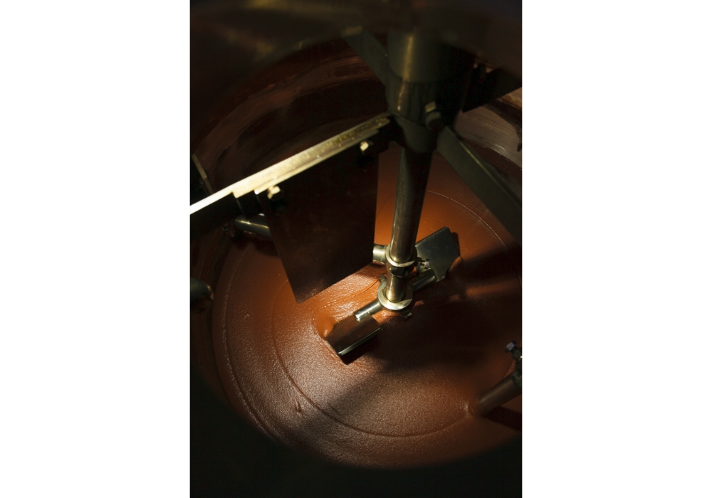 原料のうち、リンゴとトマトが６割を占める。ソース作りはまず、この２つを撹拌する作業（写真）から始まる。オートメーションではなく、作業員が一つひとつ、重い液体の缶を空け、手で加えていく。