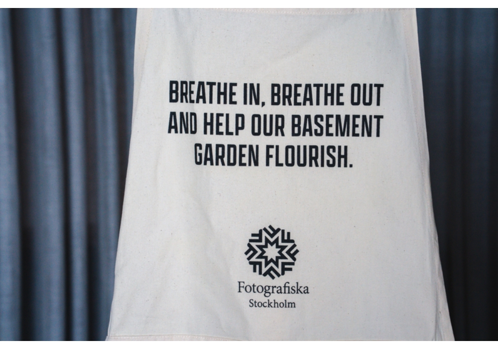 （写真）エプロンには「息を吸って、吐いて、地に花を咲かせよう」と記されている。