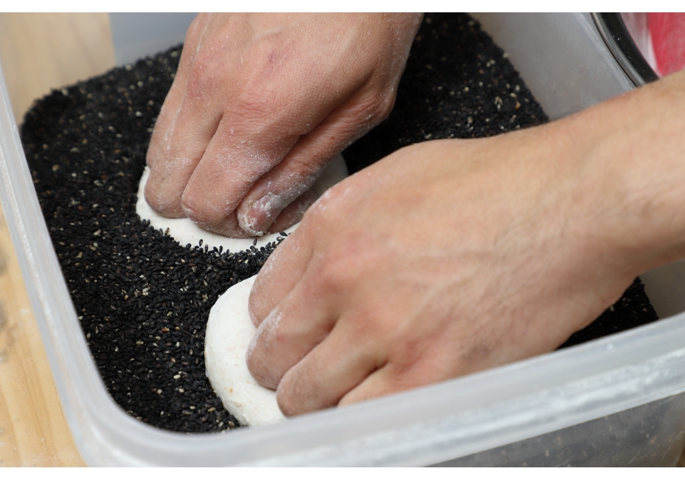 丸パンも同様に丸め、プレーンはそのまま、残りは一度片面を濡れ布巾に押し付けてから黒ゴマ、ヒマワリの種、カボチャの種を塗す