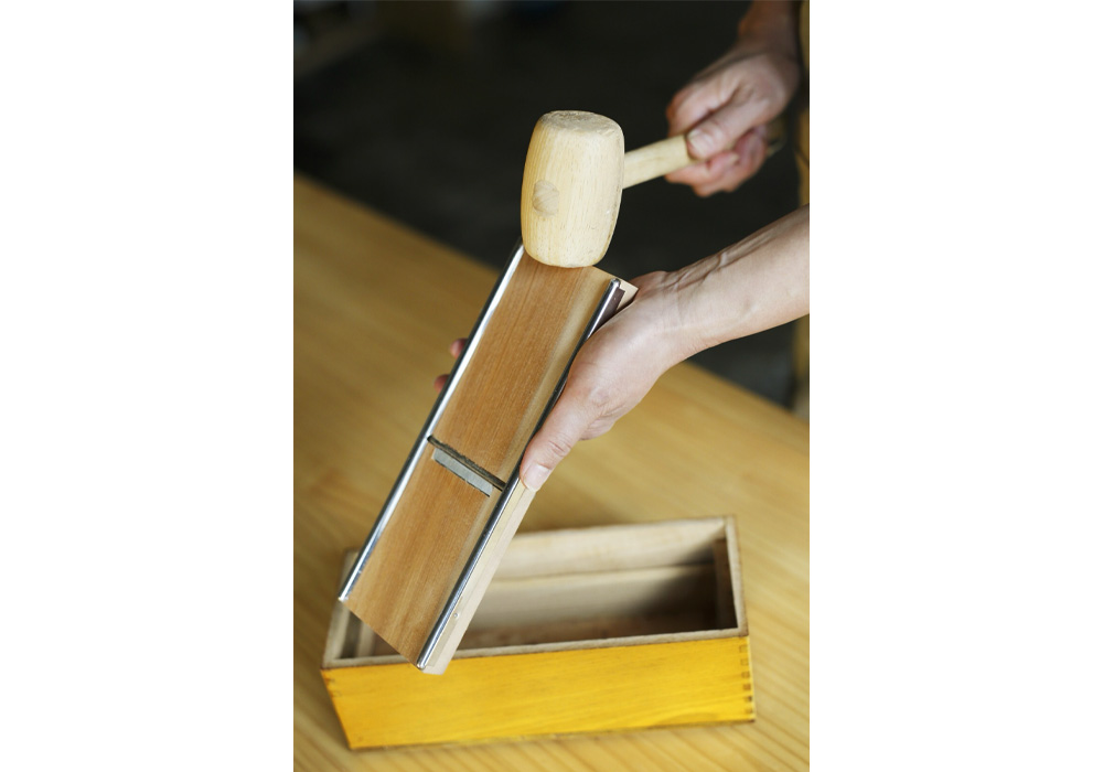 カンナの上下を木槌で叩いて調整する