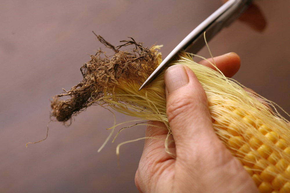 トウモロコシのひげを取る