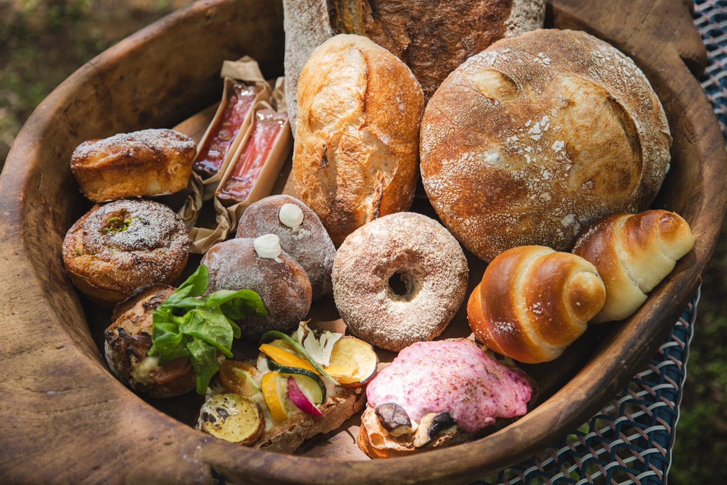 （手前右から時計回り）すべて南八ヶ岳限定パン。ポッポ牛乳たっぷり加えた白トリュフの塩パン。タルティーヌ２種（ビーツのホワイトソースと、シイタケ、ハナビラタケ／ローストしたジャガイモとキャベツ、インゲン、ラディッシュ、トマト、グラナ・パダーノとベシャメルソース）。クリームパン２種（ルバーブのジャムとシャンティイ／カスタードとシャンティイ）、ルバーブのジャムタルト。中央にドーナッツ２種（生地にカボチャを加えたプレーンと、８月に発売されたクリーム入りの白トリュフドーナツ）